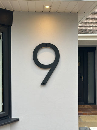 Extra large 600mm black house number '9' on a white wall of a modern bungalow.