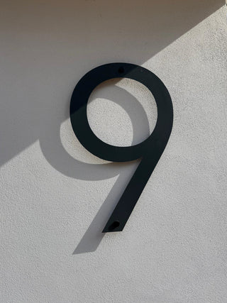 Black house number '9' on a light gray wall