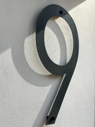 Black house number '9' on a light gray wall