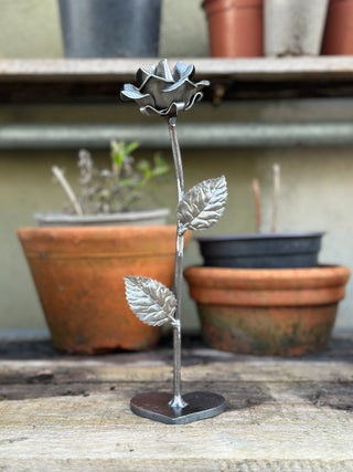 Metal rose garden sculpture sitting on rustic potting bench